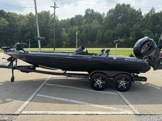 Slide: The Image of 2025 Skeeter ZXR20 boat on trailer in parking lot, surrounded by trees. - 18