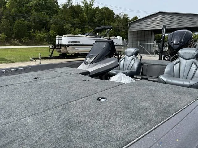 Slide: The Image of 2025 Skeeter ZXR20 boat with sleek seating and spacious deck, parked outdoors. - 14