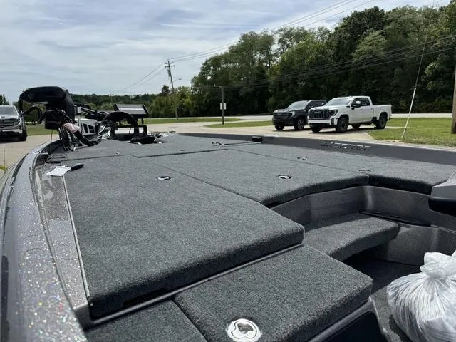 Slide: The Image of 2025 Skeeter ZXR20 boat with spacious deck, parked near road with trees and vehicles. - 18