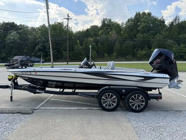 Slide: The Image of 2023 Triton 19 TrX Patriot boat on trailer, parked outdoors. - 19