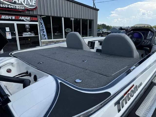 Slide: The Image of 2023 Triton 19 TrX Patriot boat with spacious deck and seating, displayed at a marine dealership. - 4