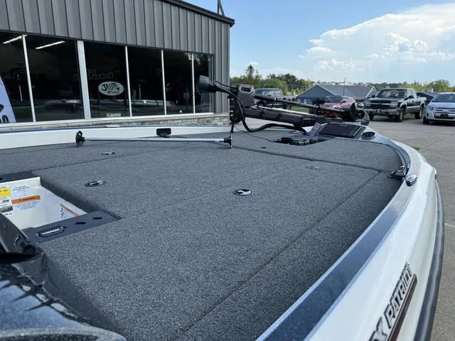 Slide: The Image of 2023 Triton 19 TrX Patriot boat deck with trolling motor, parked outside dealership. - 8