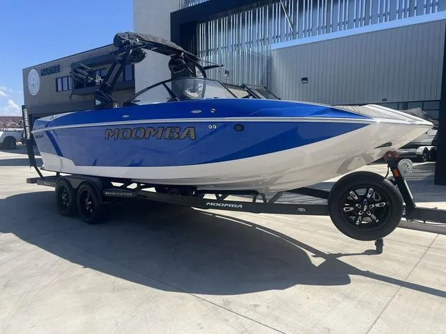 Slide: The Image of 2021 Moomba Makai boat on trailer, blue and white design, parked outdoors. - 2