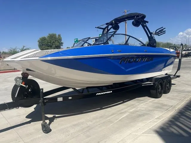 Slide: The Image of 2021 Moomba Makai boat on trailer, blue and white design, parked outdoors. - 4