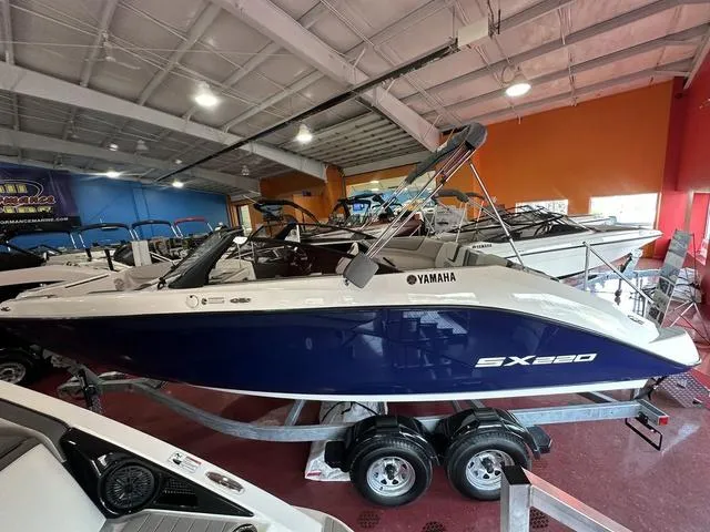Slide: The Image of 2025 Yamaha Boats SX220 in showroom, blue and white design, on trailer. - 3
