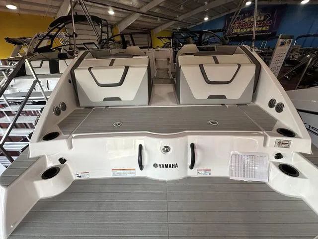 Slide: The Image of 2025 Yamaha Boats SX220, rear view in showroom, showcasing spacious deck and seating. - 4