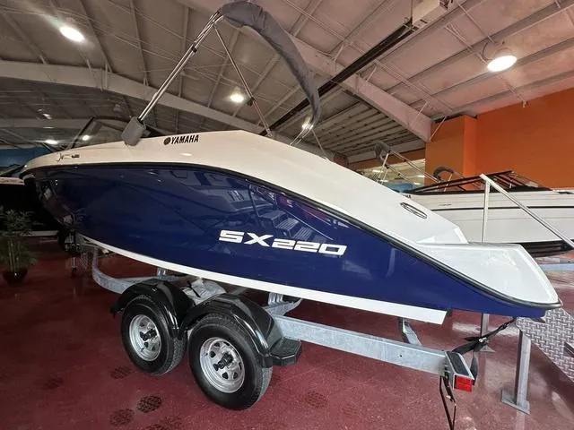 Slide: The Image of 2025 Yamaha Boats SX220 on trailer in showroom, blue and white design. - 6