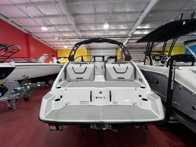 Slide: The Image of 2025 Yamaha Boats AR220 in showroom, rear view with sleek design and seating. - 10