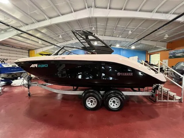 Slide: The Image of 2025 Yamaha AR220 boat in showroom, sleek black design on trailer. - 2