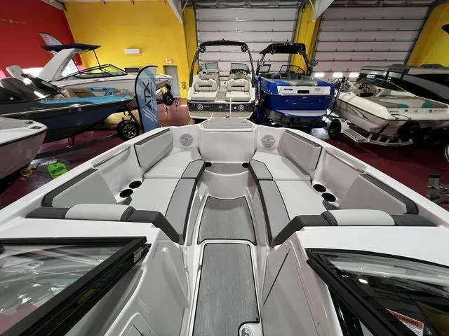 Slide: The Image of 2025 Yamaha Boats AR220 interior view in showroom with other boats. - 9