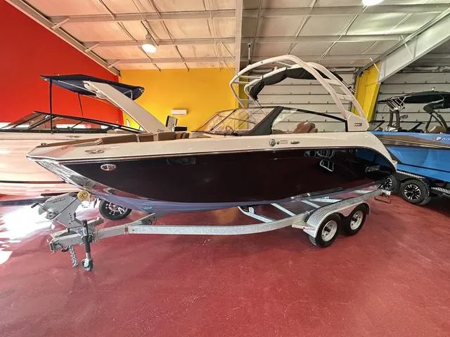 Slide: The Image of 2025 Yamaha Boats 222S in showroom, sleek black and white design on trailer. - 3