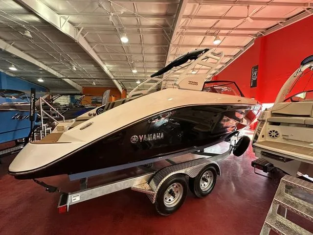Slide: The Image of 2025 Yamaha Boats 222S on trailer in showroom, sleek design, black and white exterior. - 5