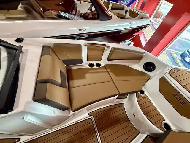 Slide: The Image of 2025 Yamaha Boats 222SD interior with tan seating and wood accents in showroom. - 12