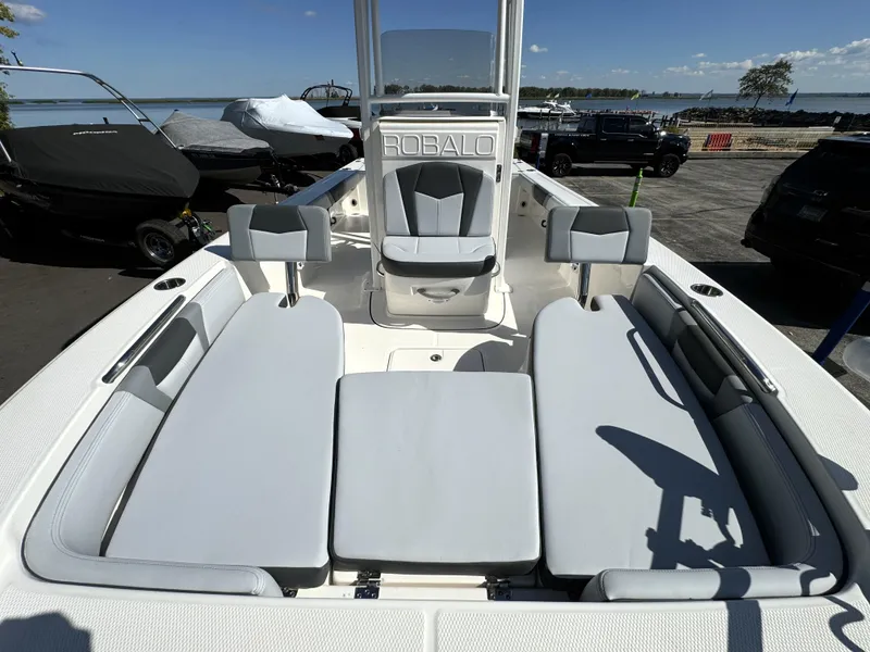 Slide: The Image of 2025 Robalo 226 Cayman boat interior with cushioned seating, docked near the shore. - 15