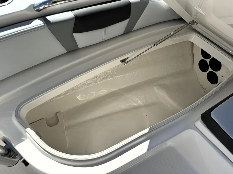 Slide: The Image of 2025 Robalo 226 Cayman boat storage compartment with open lid, showcasing spacious interior design. - 16