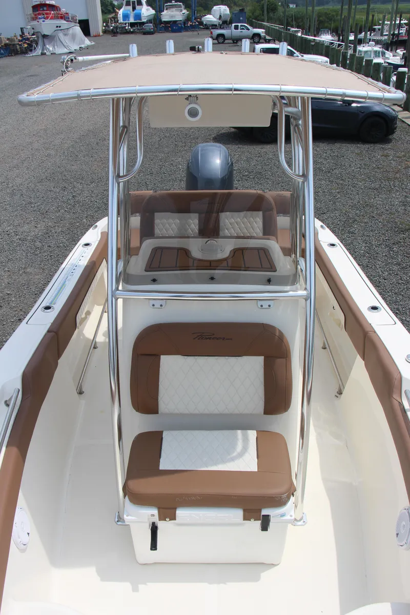 Slide: The Image of 2022 Pioneer 202 Sportfish boat with brown and white seating, docked outdoors. - 14