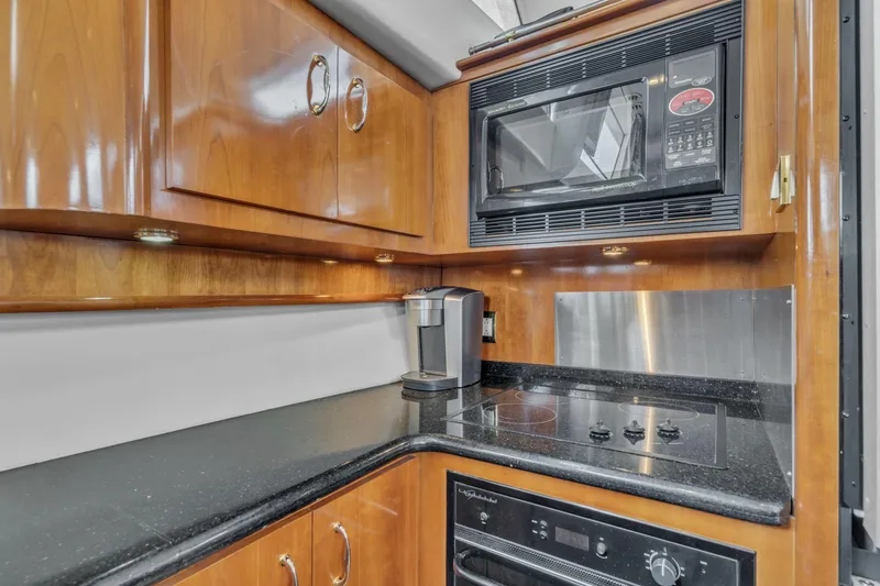 Slide: The Image of 2004 Carver 466 Motor Yacht kitchen with microwave, stove, and wooden cabinets. - 32