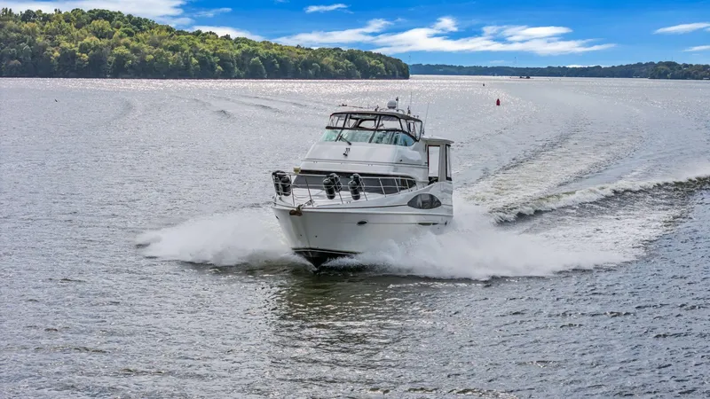 Slide: The Image of 2004 Carver 466 Motor Yacht cruising on a scenic lake under a blue sky. - 4