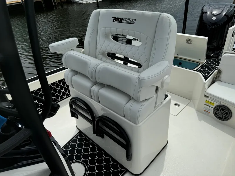 Slide: The Image of 2024 Pathfinder 2500 Hybrid boat seat with armrests and storage, docked by the water. - 26