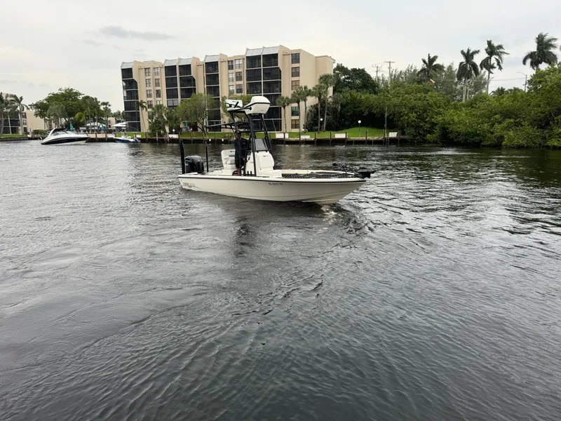 Slide: The Image of 2024 Pathfinder 2500 Hybrid boat cruising on a river near residential buildings. - 4