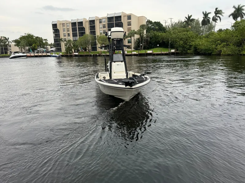 Slide: The Image of 2024 Pathfinder 2500 Hybrid boat cruising on a calm river near waterfront buildings. - 5