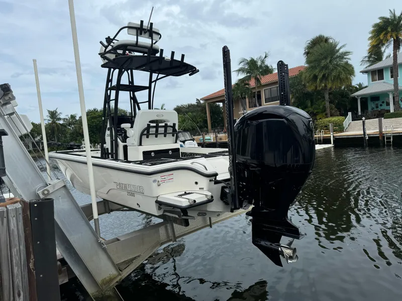 Slide: The Image of 2024 Pathfinder 2500 Hybrid boat on lift by waterfront homes. - 8