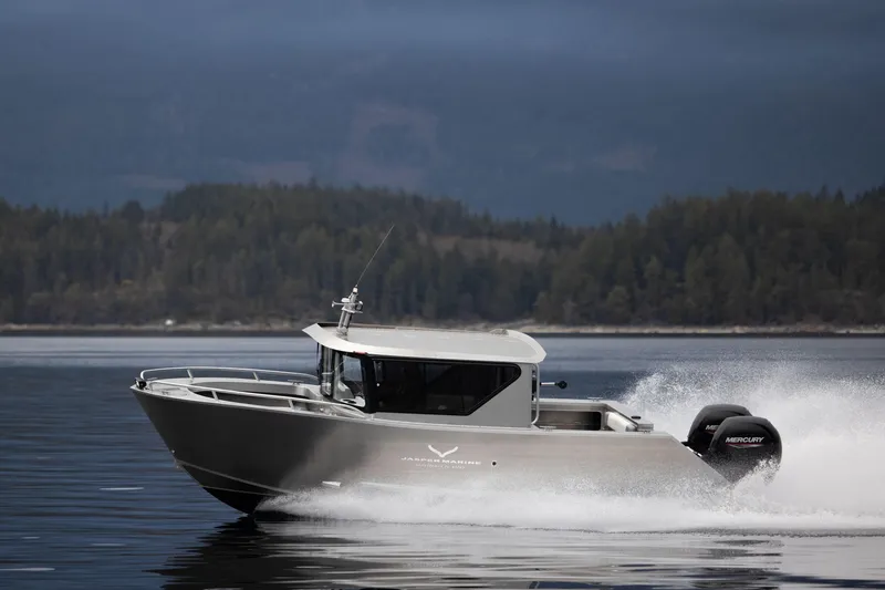 Slide: The Image of 2025 Jasper Marine Defender 22 speeding on a serene lake with forested backdrop. - 22