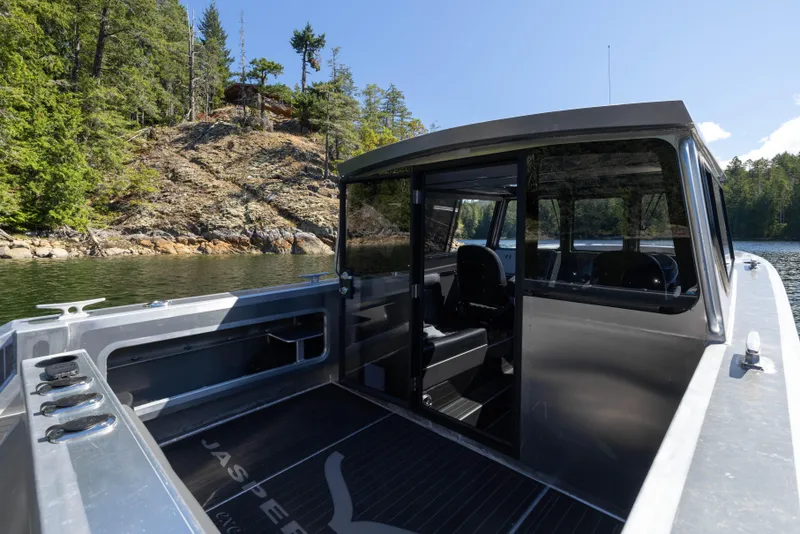 Slide: The Image of 2025 Jasper Marine Defender 22 boat on scenic lake with forested shoreline. - 28