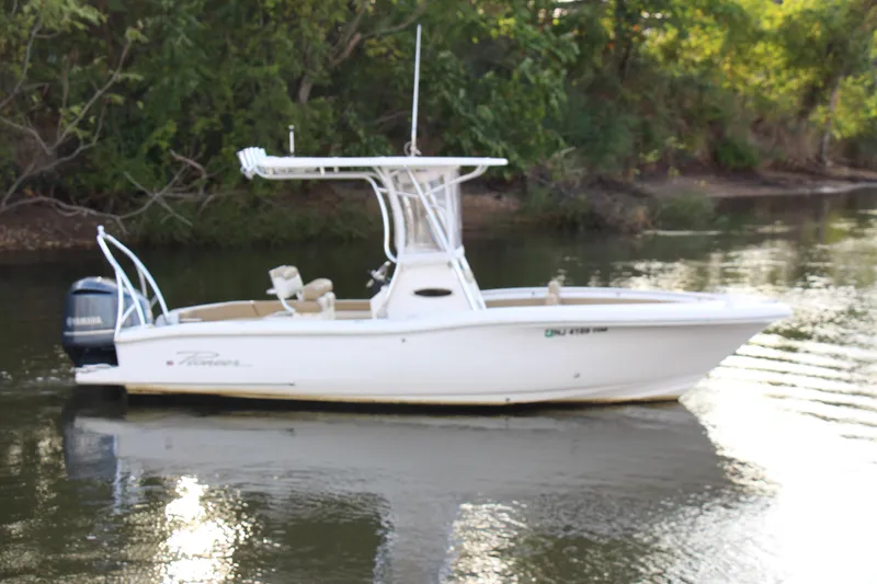 Slide: The Image of 2020 Pioneer 222 Sportfish boat on calm water, surrounded by lush greenery. - 0