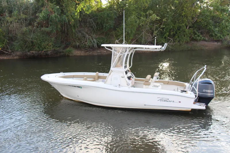 Slide: The Image of 2020 Pioneer 222 Sportfish boat on a calm river, surrounded by lush greenery. - 8