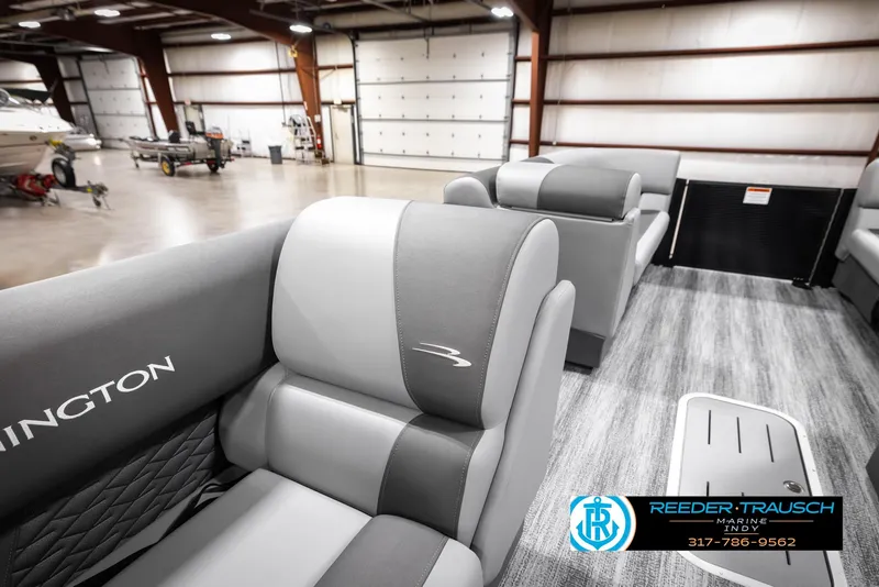 Slide: The Image of 2025 Bennington 21 SL boat interior with gray seating in a spacious warehouse. - 21