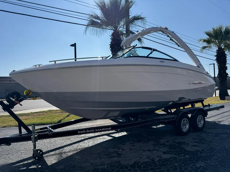 Slide: The Image of 2025 Regal LS4 boat on trailer, parked outdoors near palm trees. - 2