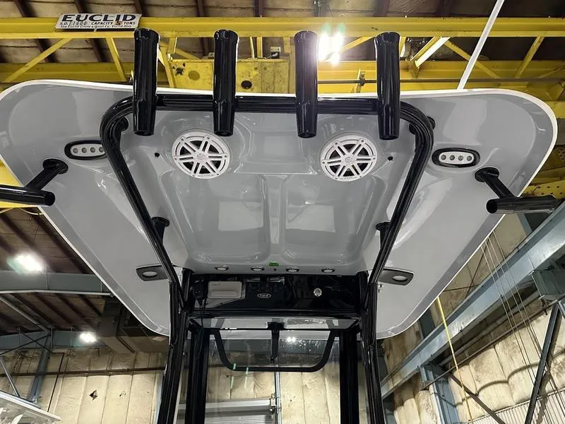 Slide: The Image of 2025 Sea Hunt Ultra 239se boat roof with speakers and rod holders in a warehouse. - 12