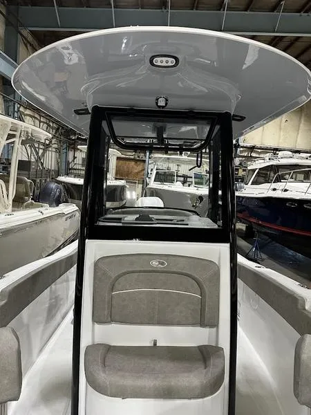 Slide: The Image of 2025 Sea Hunt Ultra 239se boat interior with seating and console in a showroom. - 17