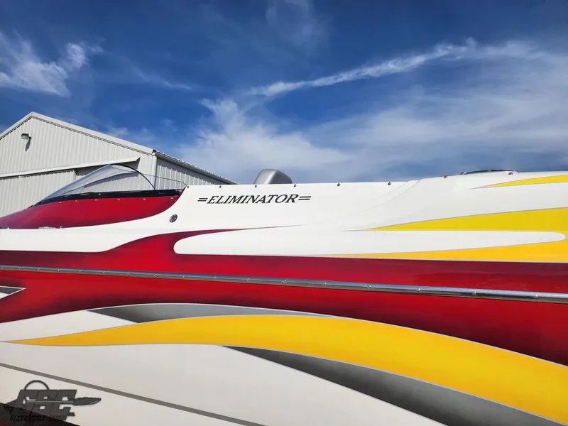Slide: The Image of 2005 Eliminator Daytona 30 boat with vibrant red and yellow design under a clear blue sky. - 13