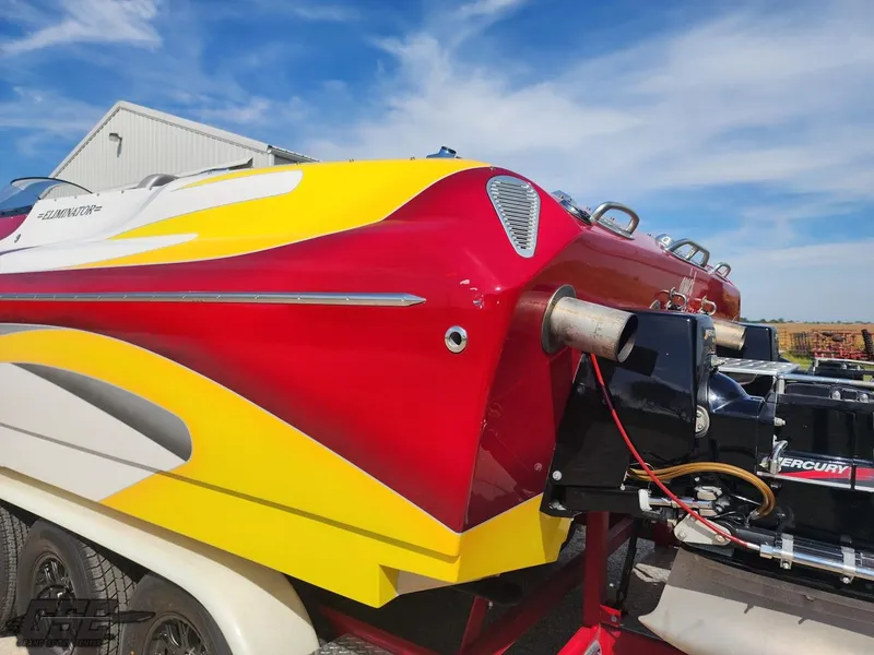 Slide: The Image of 2005 Eliminator Daytona 30 speedboat with vibrant red and yellow design, parked outdoors. - 14