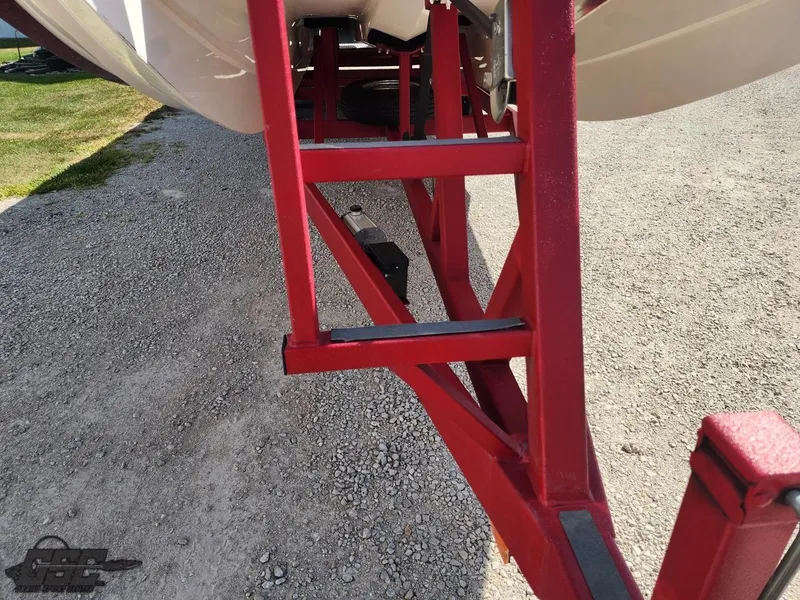 Slide: The Image of Red trailer frame supporting a 2005 Eliminator Daytona 30 boat on gravel. - 18