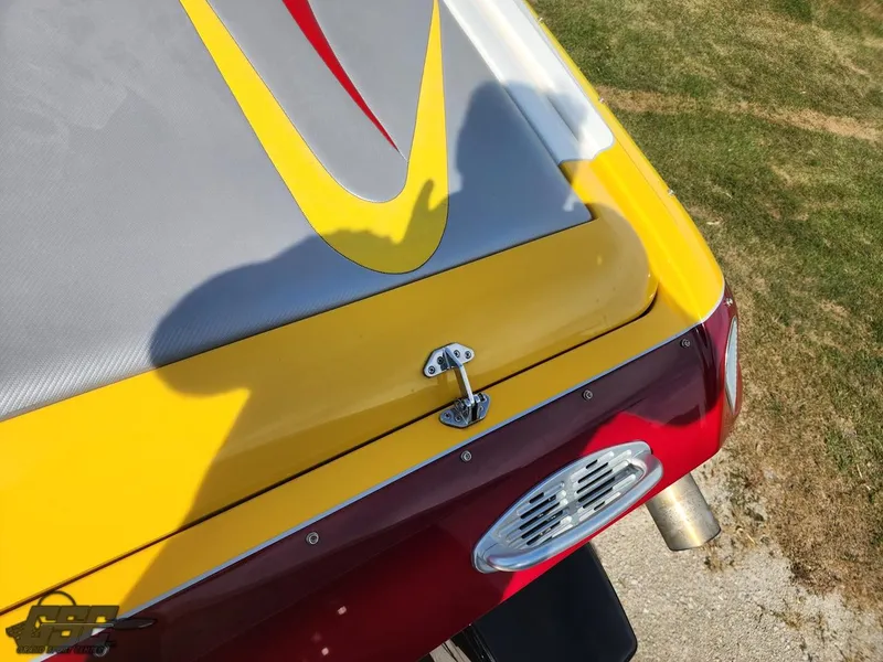 Slide: The Image of 2005 Eliminator Daytona 30 boat with vibrant yellow and red design on grass. - 47