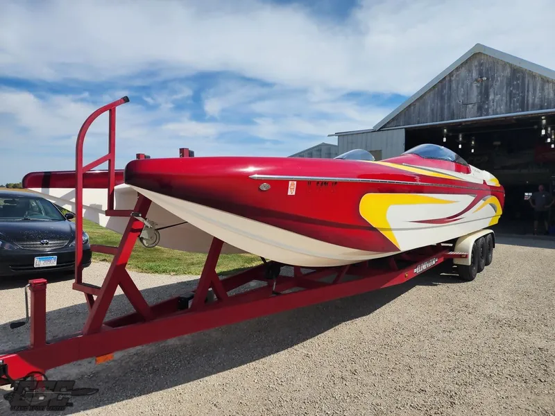 Slide: The Image of 2005 Eliminator Daytona 30 speedboat on trailer, vibrant red and yellow design, parked outdoors. - 5
