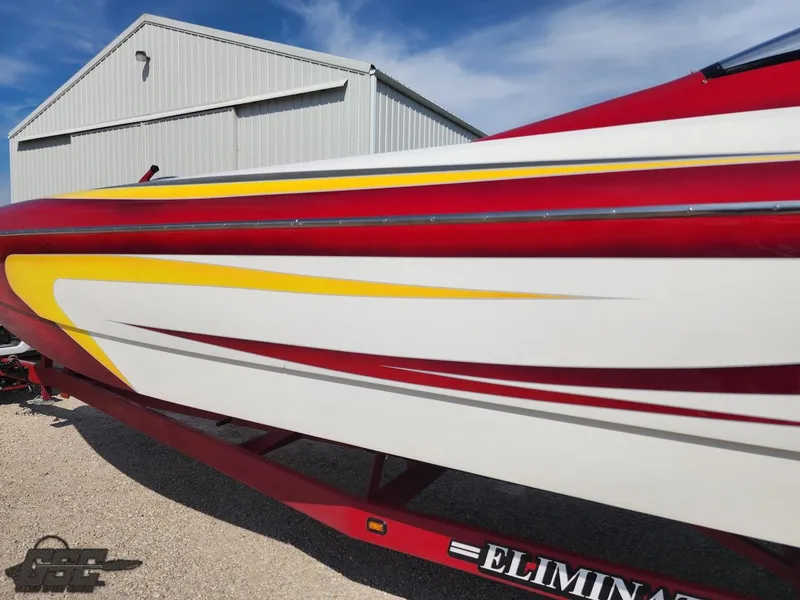 Slide: The Image of 2005 Eliminator Daytona 30 boat with red and yellow accents, parked near a metal building. - 8