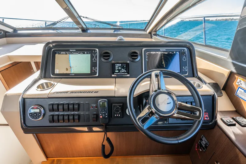 Slide: The Image of Cockpit of 2016 Sea Ray 400 Sundancer with navigation screens and steering wheel. - 21