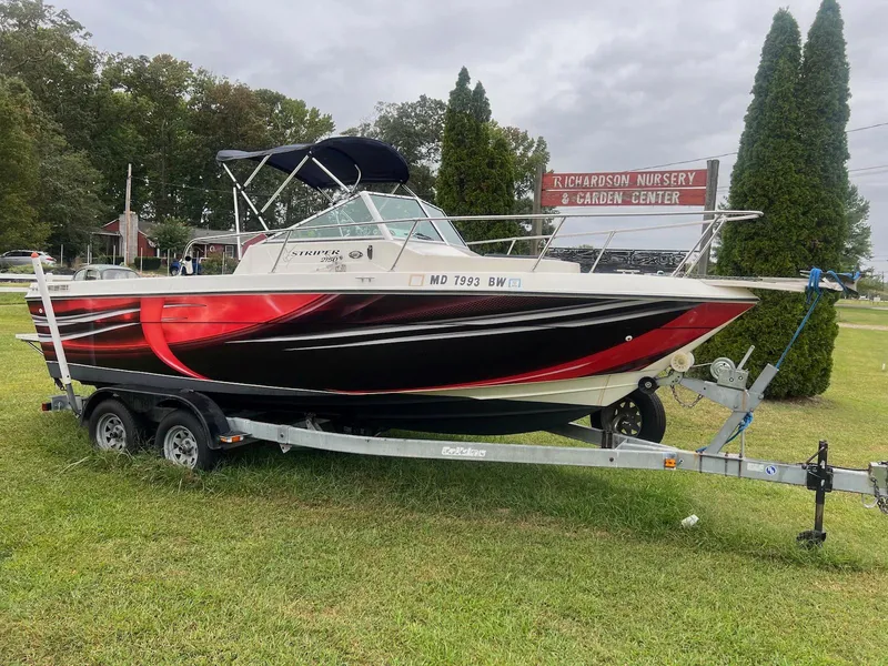 The Image of 1998 Seaswirl Striper 2150 Walkaround boat on trailer, parked on grass near nursery sign. - 0