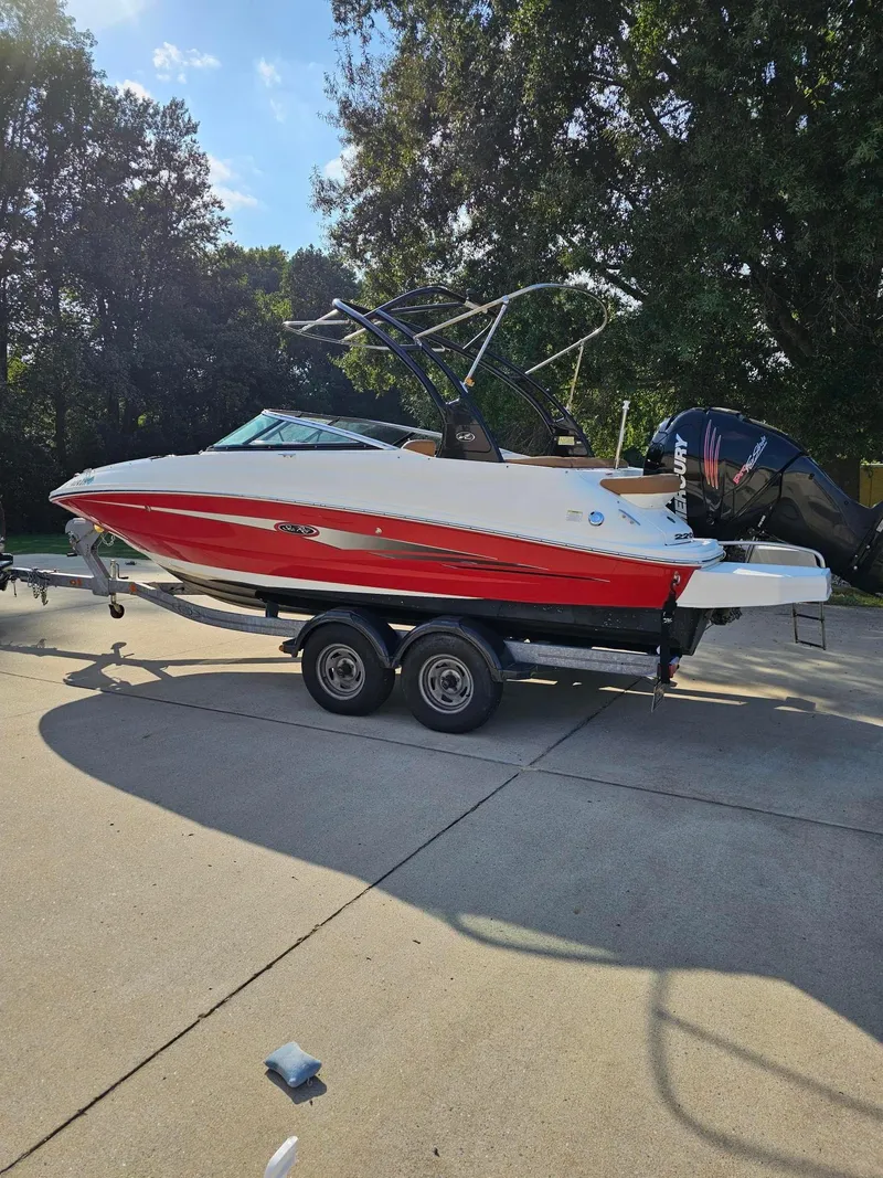 Slide: The Image of 2014 Sea Ray 220 Sundeck Outboard boat on trailer, red and white, parked outdoors. - 4