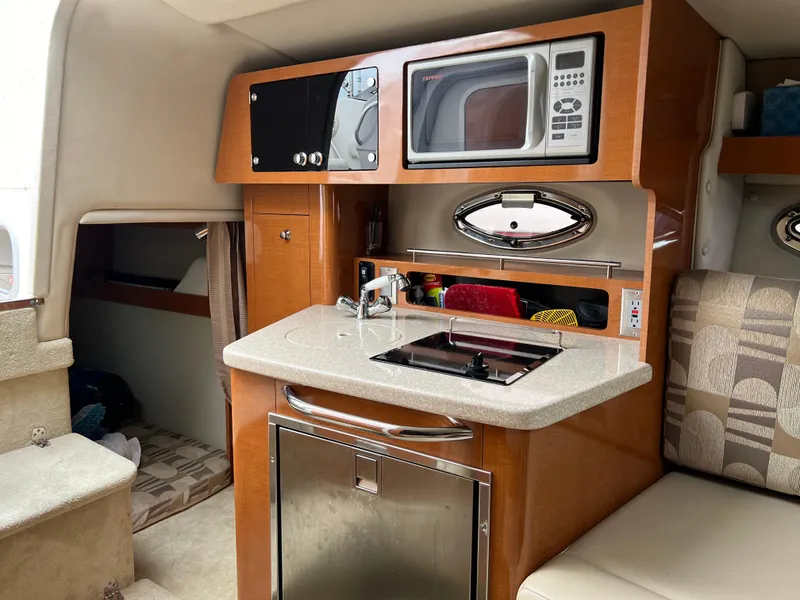 Slide: The Image of 2007 Chaparral Signature 250 cabin kitchen with microwave, sink, and compact fridge. - 15