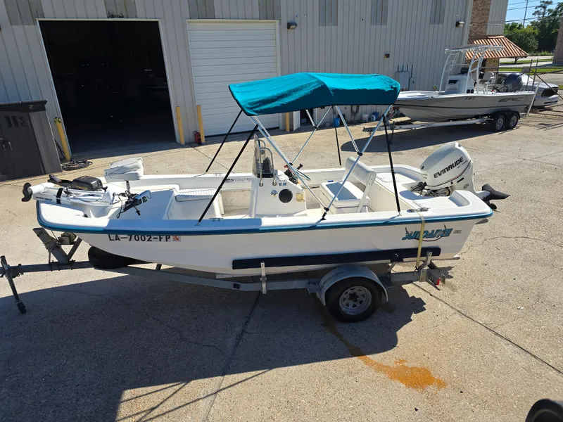 Slide: The Image of 2007 Sundance B18CC boat with blue canopy on trailer, parked outside a garage. - 4