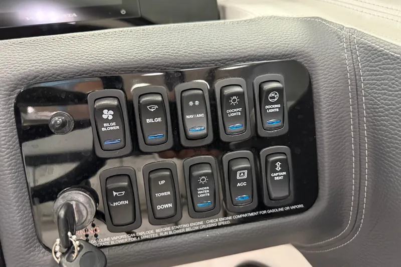 Slide: The Image of Control panel of 2025 Regal LS2 Surf boat with labeled switches and key ignition. - 42
