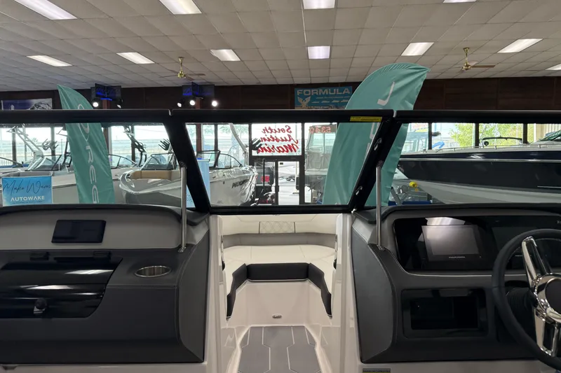 Slide: The Image of 2025 Regal LS2 Surf boat interior in showroom, featuring modern dashboard and seating. - 49