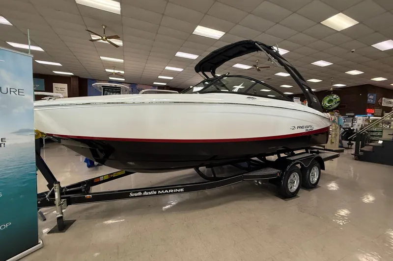 Slide: The Image of 2025 Regal LS2 Surf boat displayed indoors on a trailer. - 63