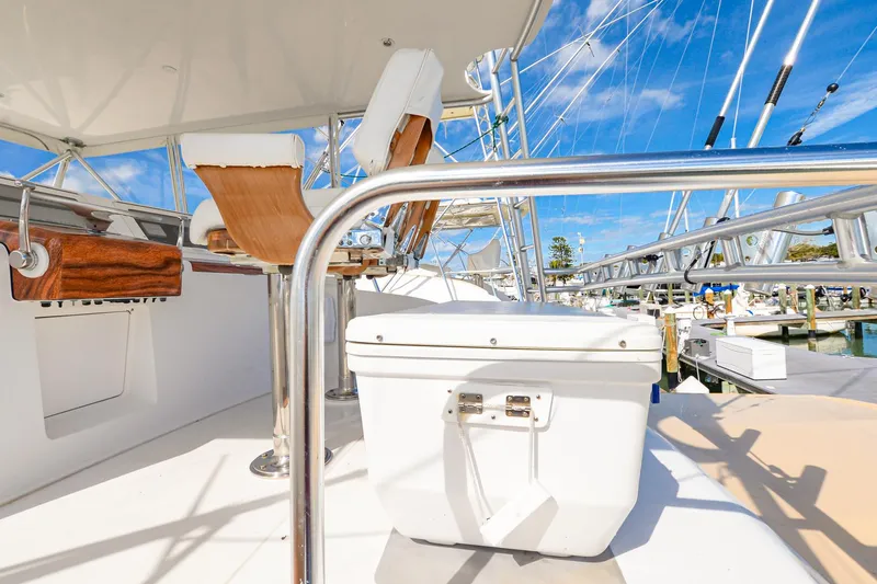 Slide: The Image of 1999 Viking 55 Convertible yacht deck with seating and cooler, under clear blue sky. - 12