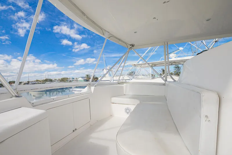 Slide: The Image of 1999 Viking 55 Convertible yacht interior with white seating, blue sky, and marina view. - 17